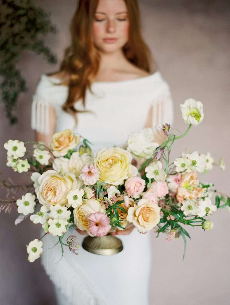 Bride holding a bridal bouquet of blush and cream garden roses with wildflowers