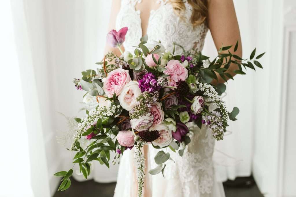 Bride holding pink garden rose bouquet with deep purple accents