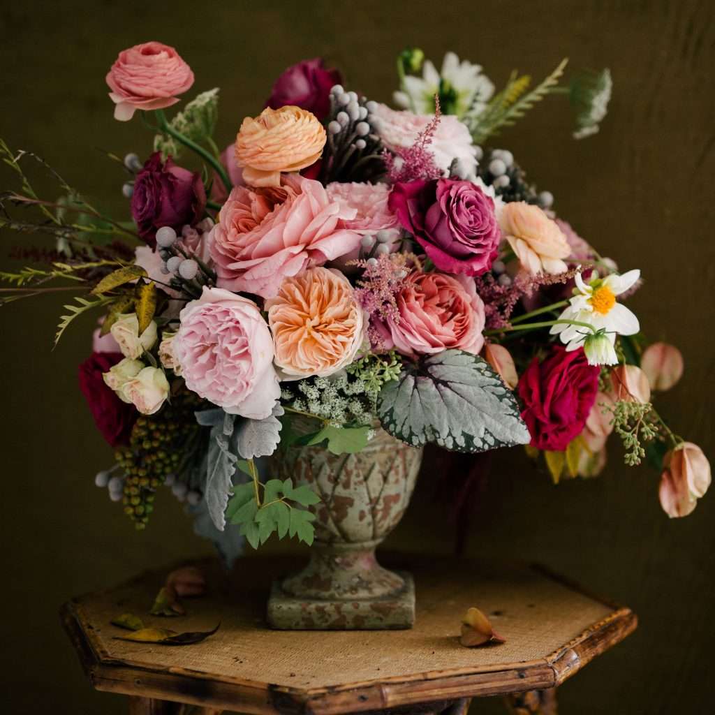 Moody urn arrangement of pink and burgundy garden roses with ranunculus, Katherine Taylor entry