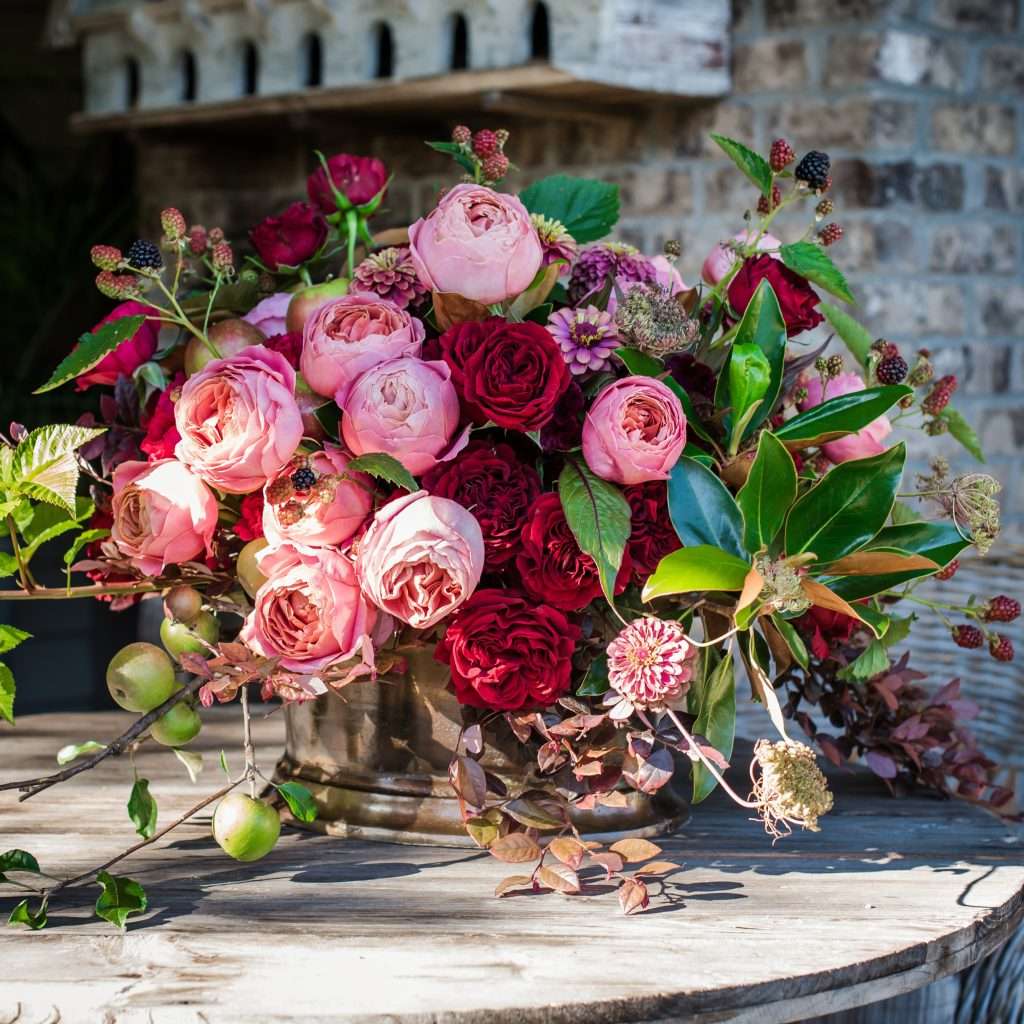 Rustic tablescape arrangement of pink and red garden roses with blackberries and magnolia leaves, Charlie Groppetti entry