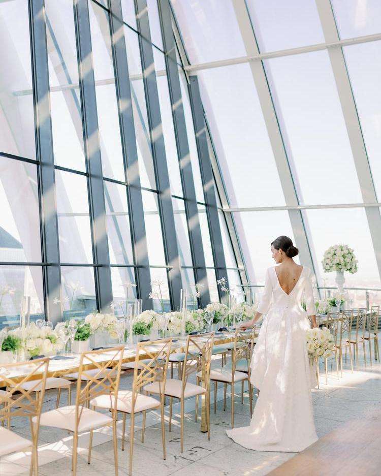 Bride walking past reception table beneath the Sky Garden's glass windows