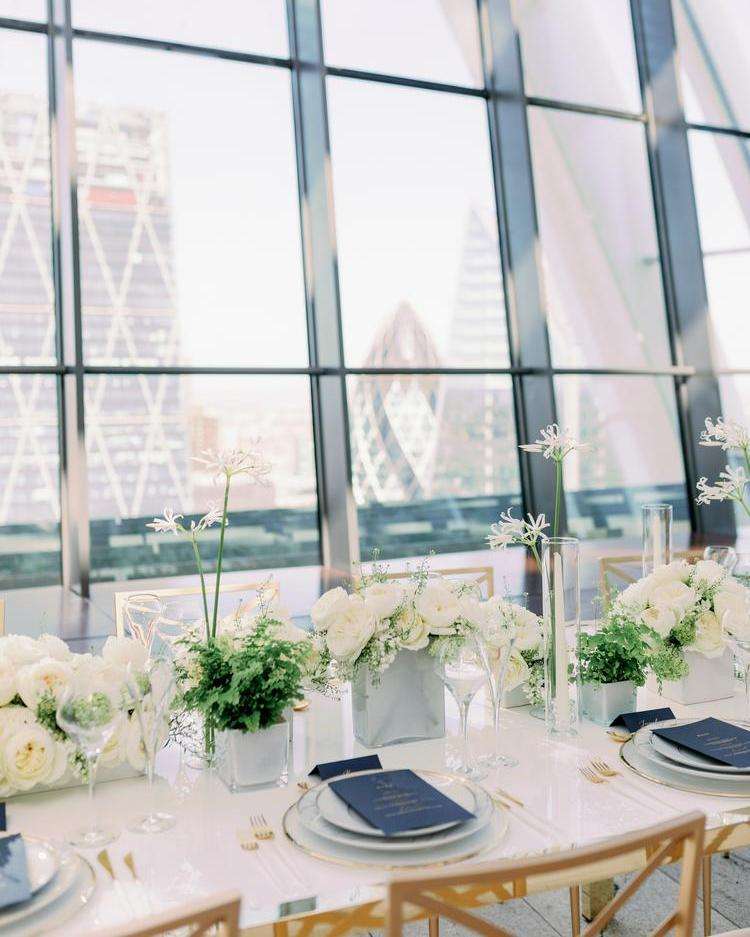Reception table with white garden rose centerpieces overlooking the London skyline