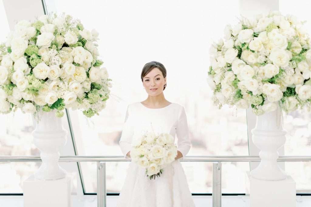 Bride at Sky Garden venue flanked by tall white urns of garden roses