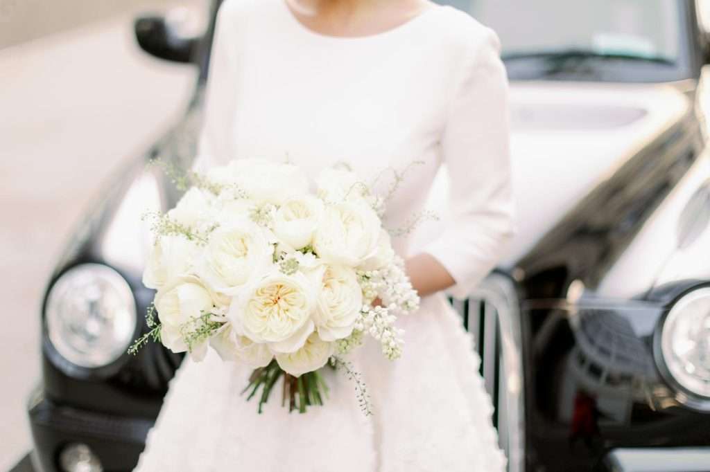 Close-up of ivory Leonora garden rose bouquet against black cab and white gown