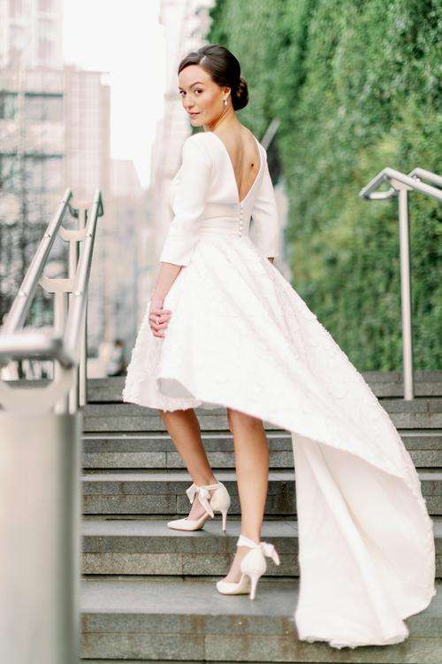 Bride glancing back while descending city stairs in a high-low gown