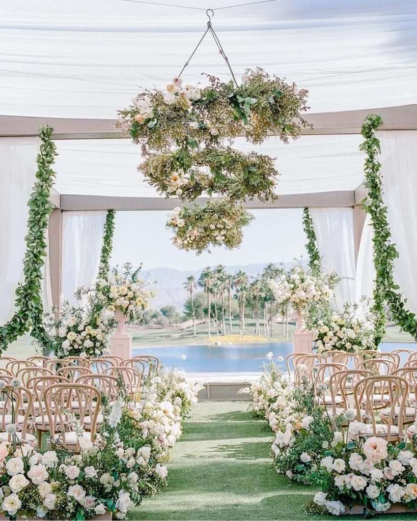 Hanging floral chandelier over rows of chairs at the lakeside ceremony