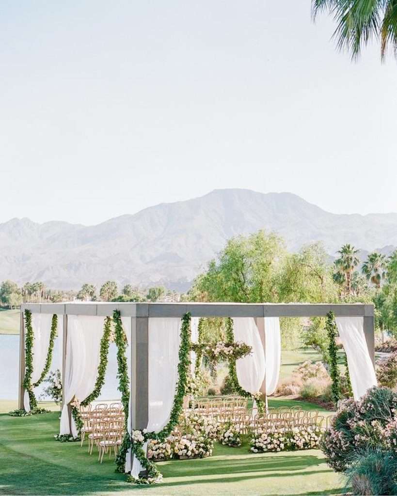 Draped ceremony pavilion with greenery garlands overlooking desert mountains