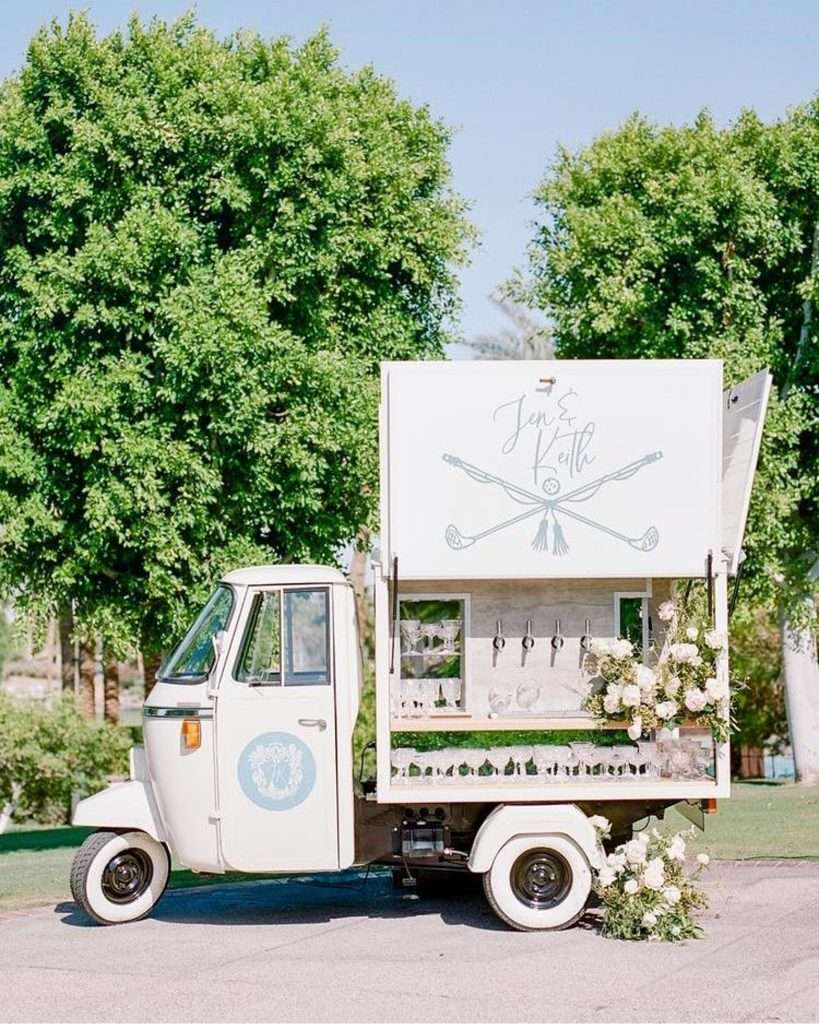 Vintage cocktail cart branded Jen and Keith parked beneath shade trees