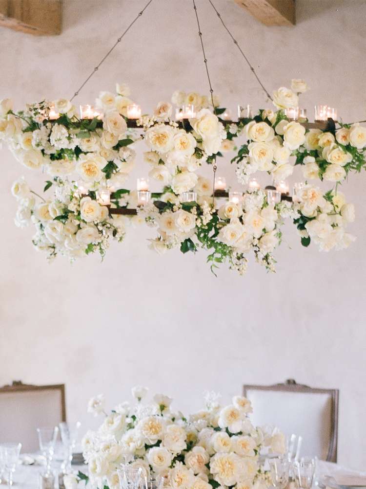 White garden rose floral chandelier with candles over a wedding reception table