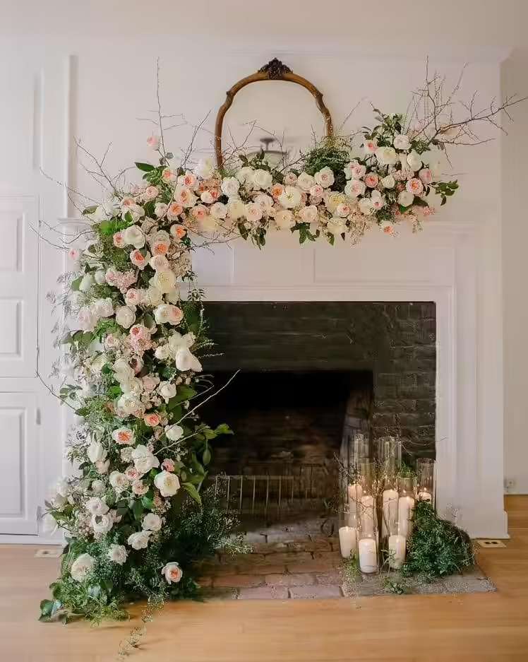 Garden rose and branch installation draped over a mantel with candles below