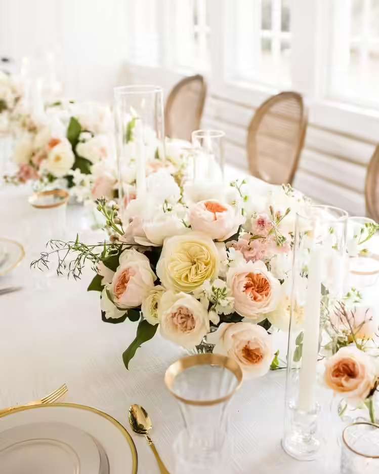 Long reception table set with blush and ivory garden rose centerpieces and taper candles