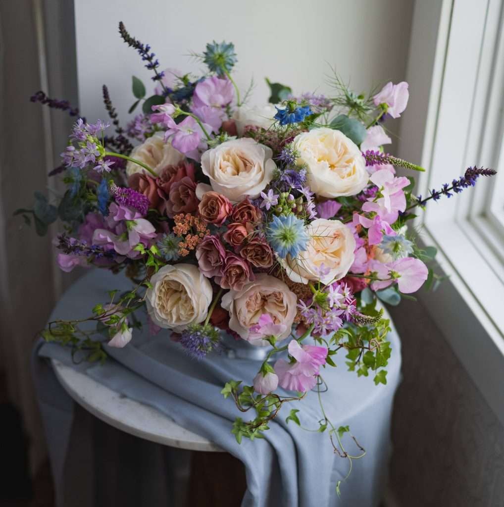 Mauve and lavender garden rose arrangement with sweet peas on marble table