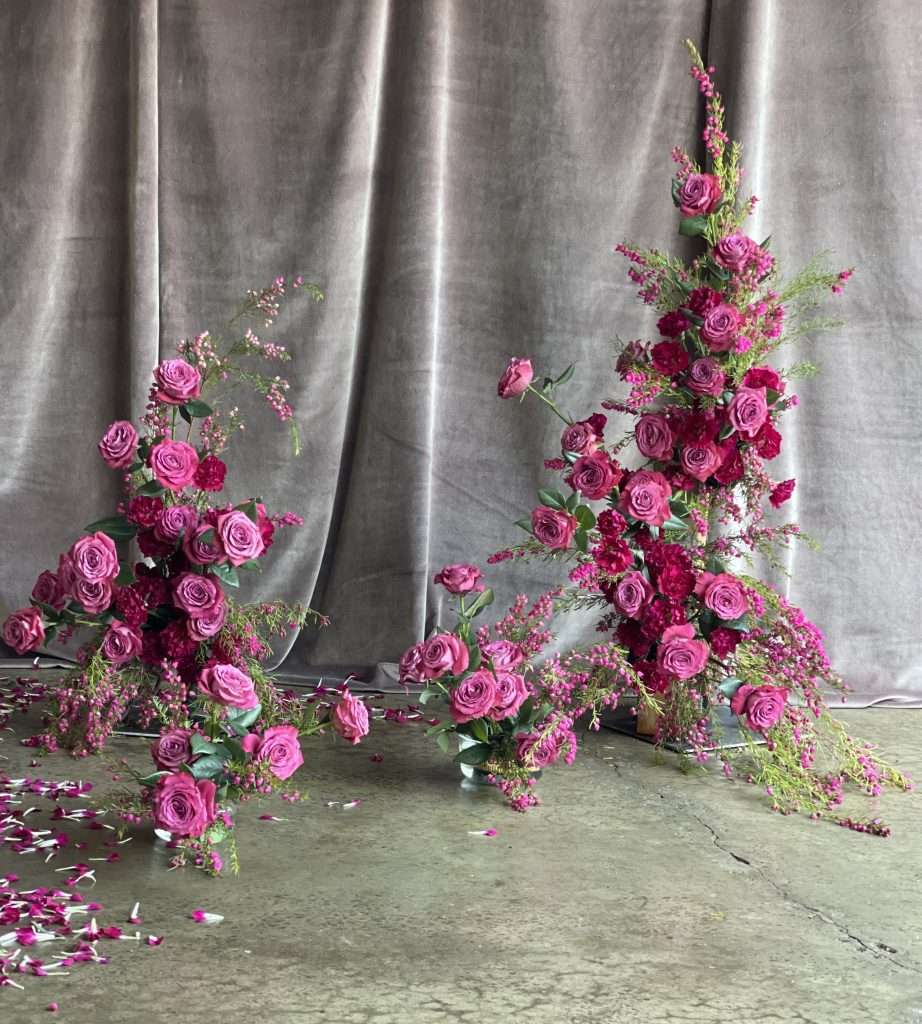Magenta and fuchsia garden rose floral towers against a grey velvet backdrop