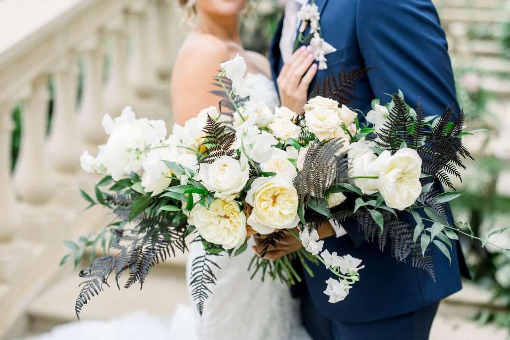 Bride and groom with white garden rose bouquet accented with dark fern