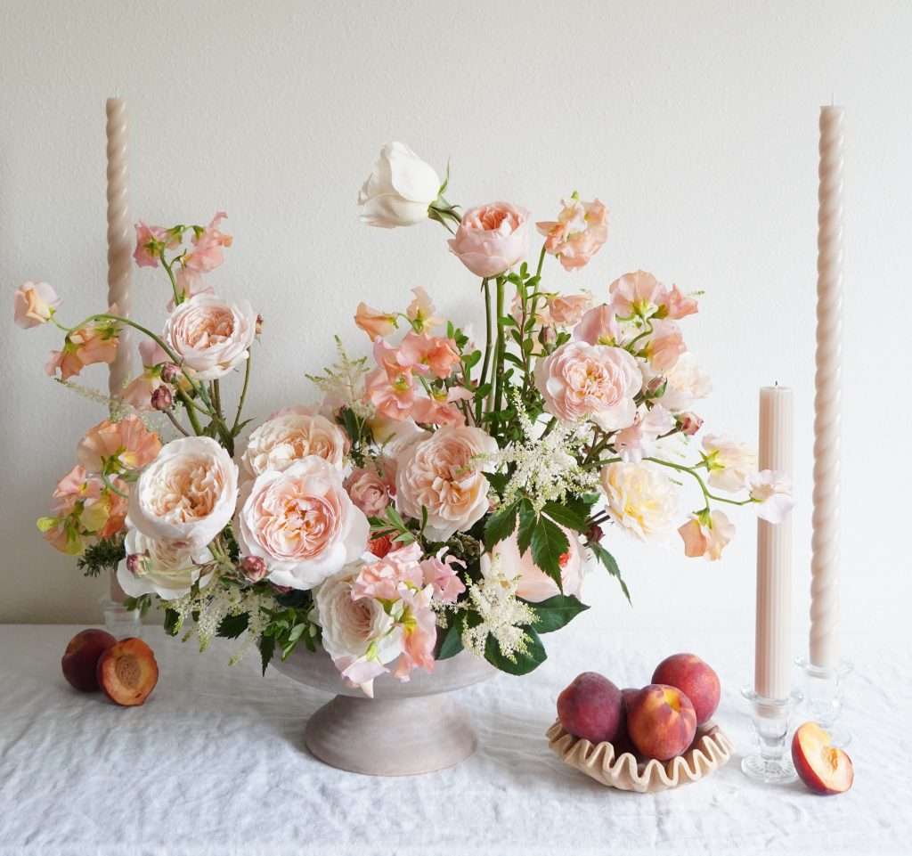 Peach garden rose centerpiece with sweet peas, peaches and taper candles