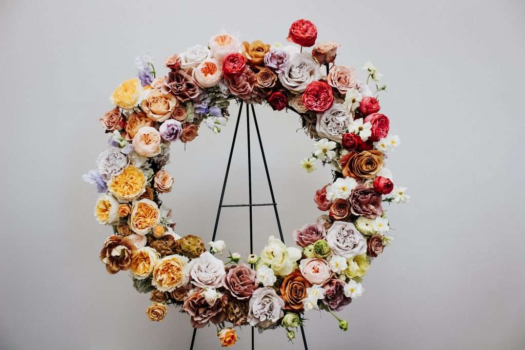 Circular wreath of multicolored garden roses on a black easel stand
