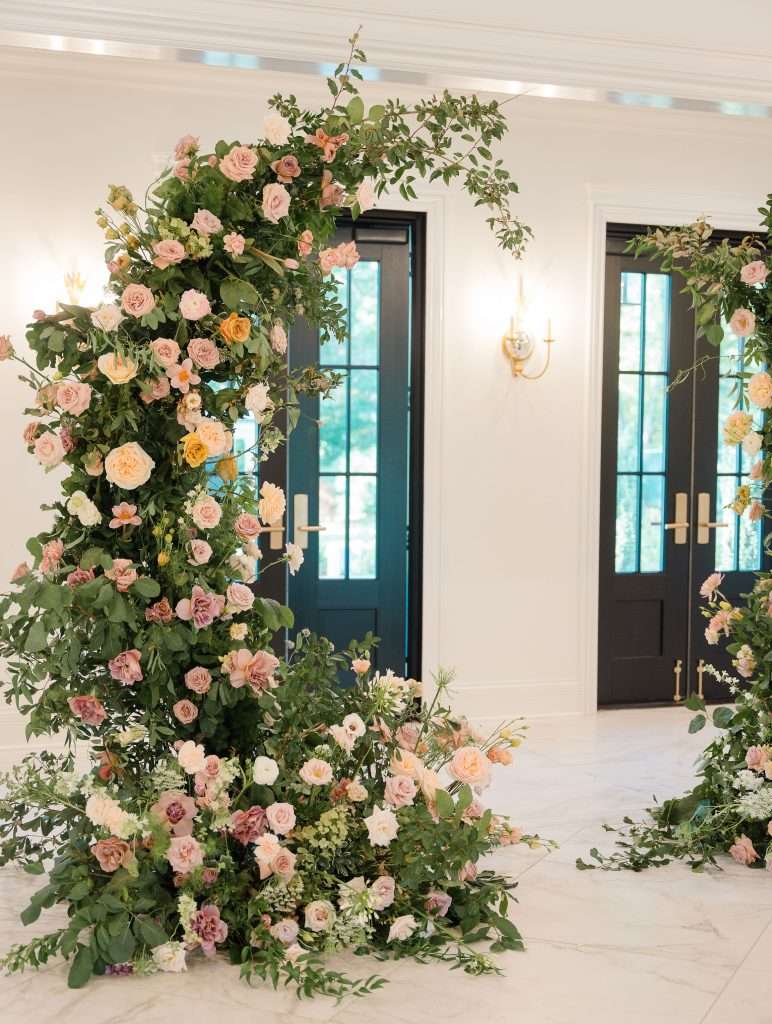 Indoor floral installation of blush and mauve garden roses cascading down a wall