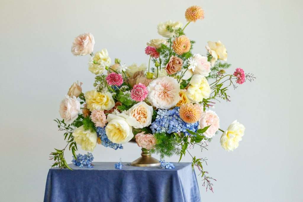 Pastel centerpiece with hydrangea, dahlias and garden roses on a draped table