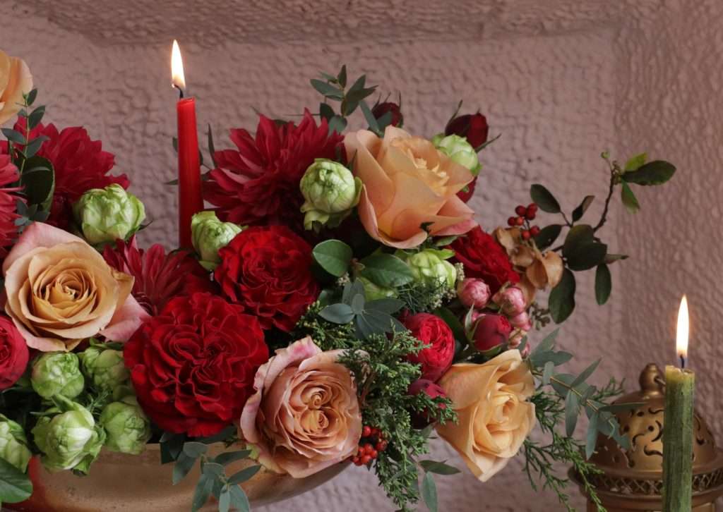 Rich red and peach garden rose centerpiece with dahlias and lit taper candles