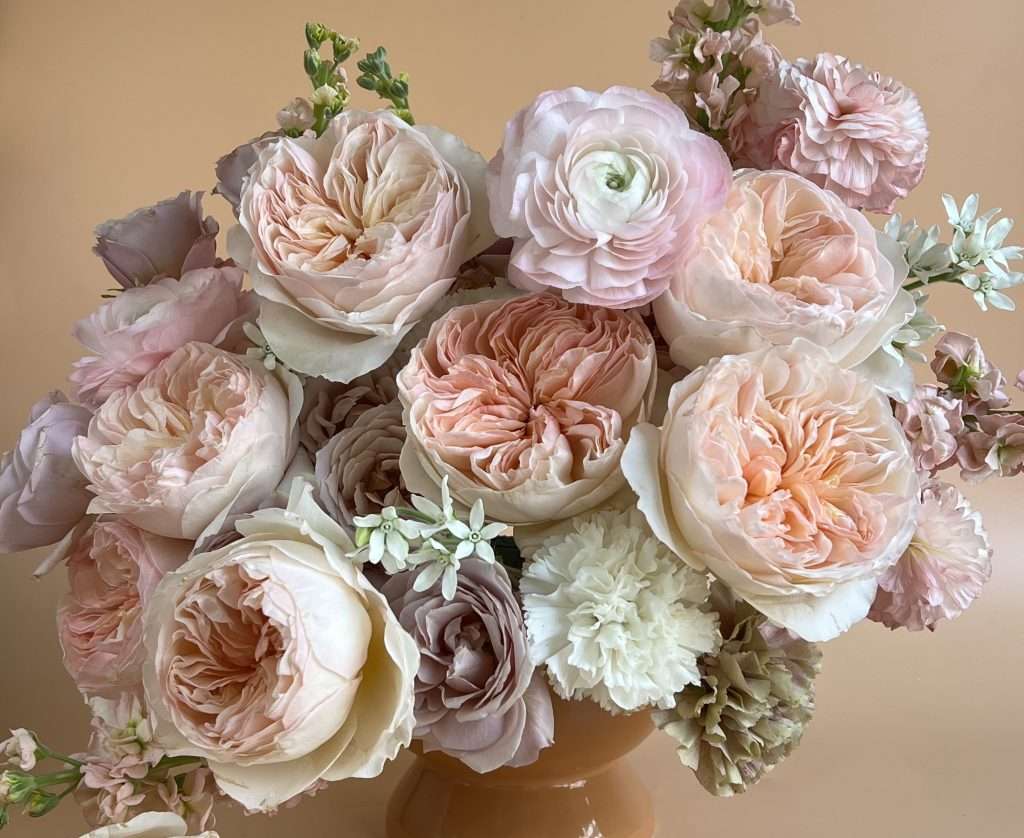 Peach and blush wedding centerpiece with garden roses and ranunculus