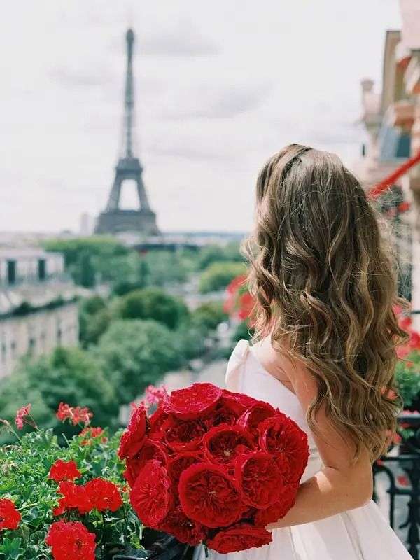 Bride with red garden rose bouquet on a Paris balcony overlooking the Eiffel Tower