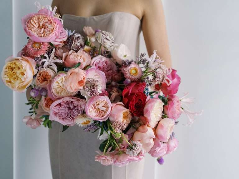 A cascading bouquet of pink, lavender and cream garden roses held against a satin gown.