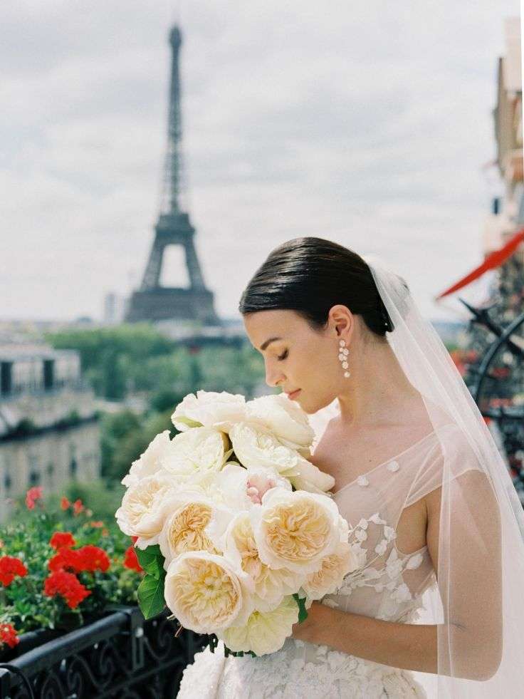 Bride on a Paris balcony by the Eiffel Tower holding a cream David Austin garden rose bouquet