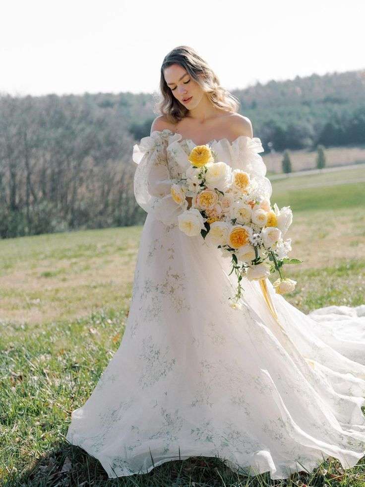 Bride in off-shoulder gown holding cascading ivory and yellow garden rose bouquet