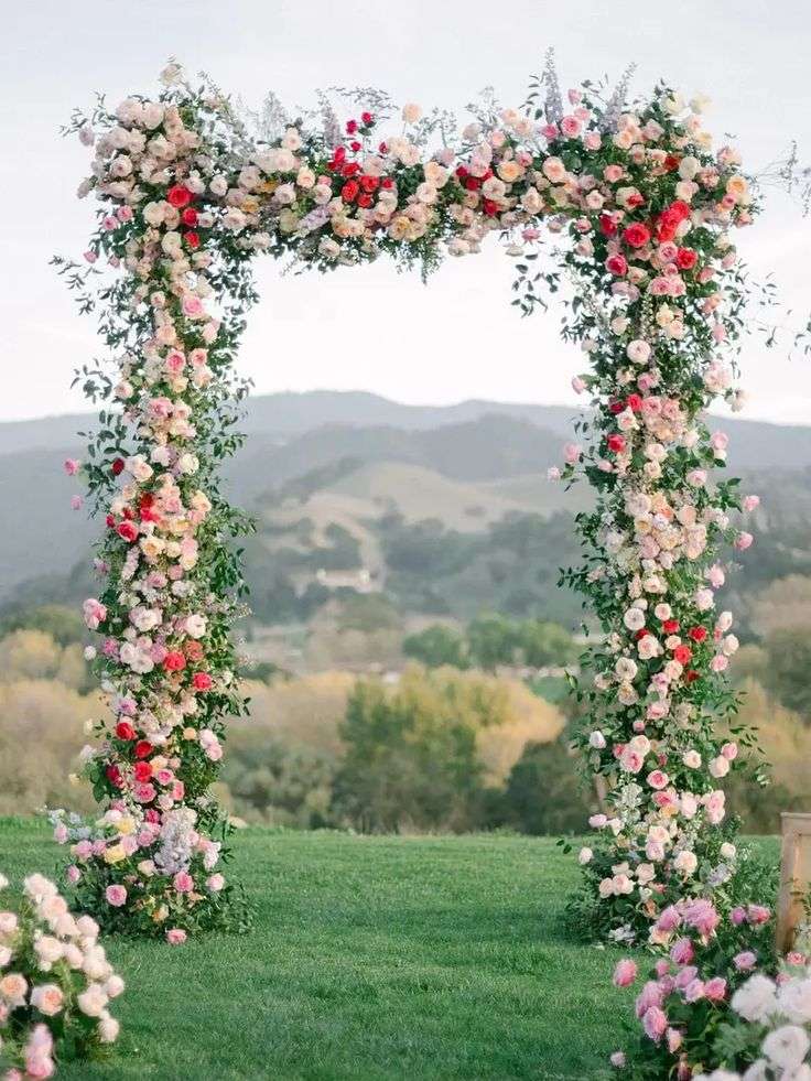 Square wedding arch dressed in red, pink and blush garden roses on a hillside lawn