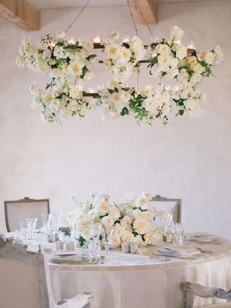 Hanging floral chandelier of cream garden roses above a candlelit reception table