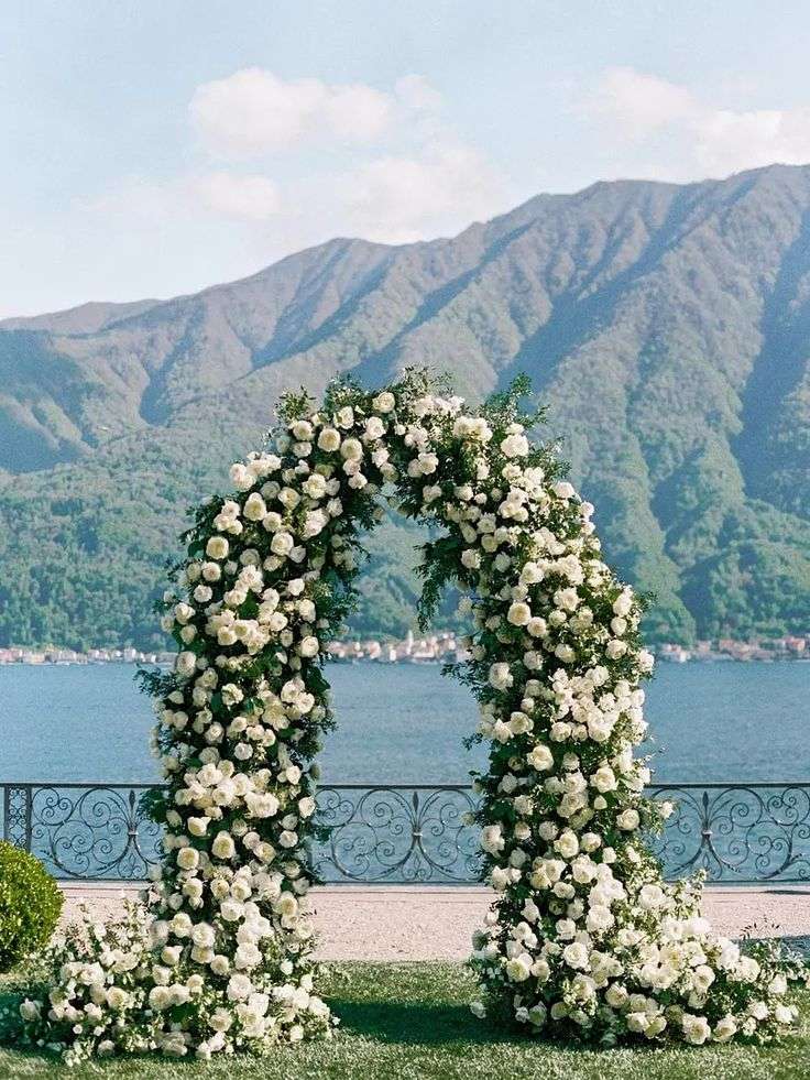 Round white garden rose arch overlooking a lake and mountains