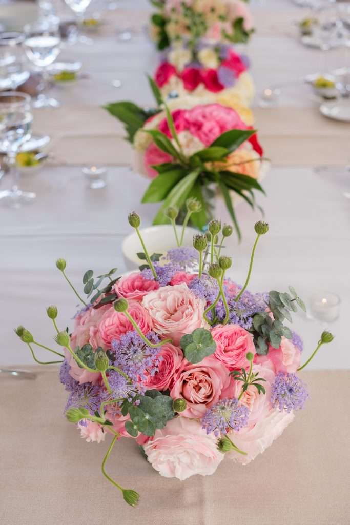 Pink garden rose centerpieces with agapanthus and eucalyptus on a wedding table