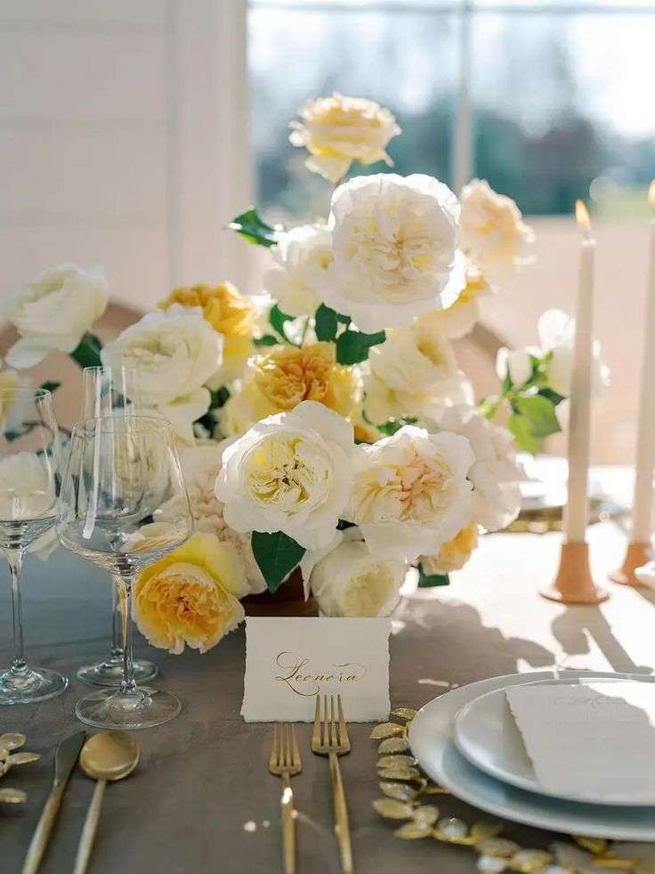 Place setting with yellow and cream garden roses, gold flatware and a calligraphy place card