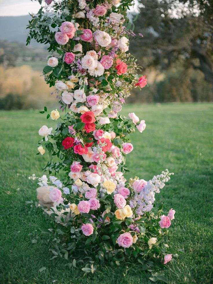 Cascading pink, coral and yellow garden rose installation on a lawn