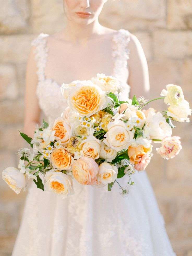 Bride holding a peach and cream garden rose bouquet with wildflower accents
