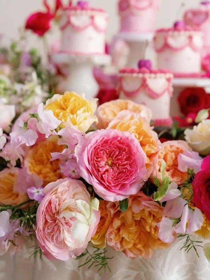 Close-up of pink and yellow garden roses beside pink-frosted mini cakes
