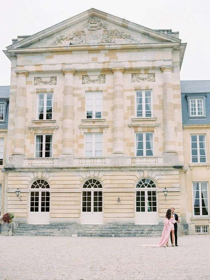 Bride and groom in pink gown before a grand French chateau facade