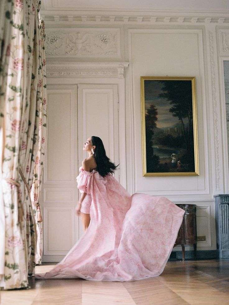 Bride in flowing pink gown in an ornate chateau interior with a framed painting