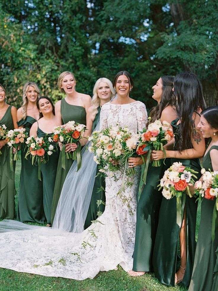 A wedding party outdoors, the attendants in green gowns holding bouquets of cream and coral garden roses.