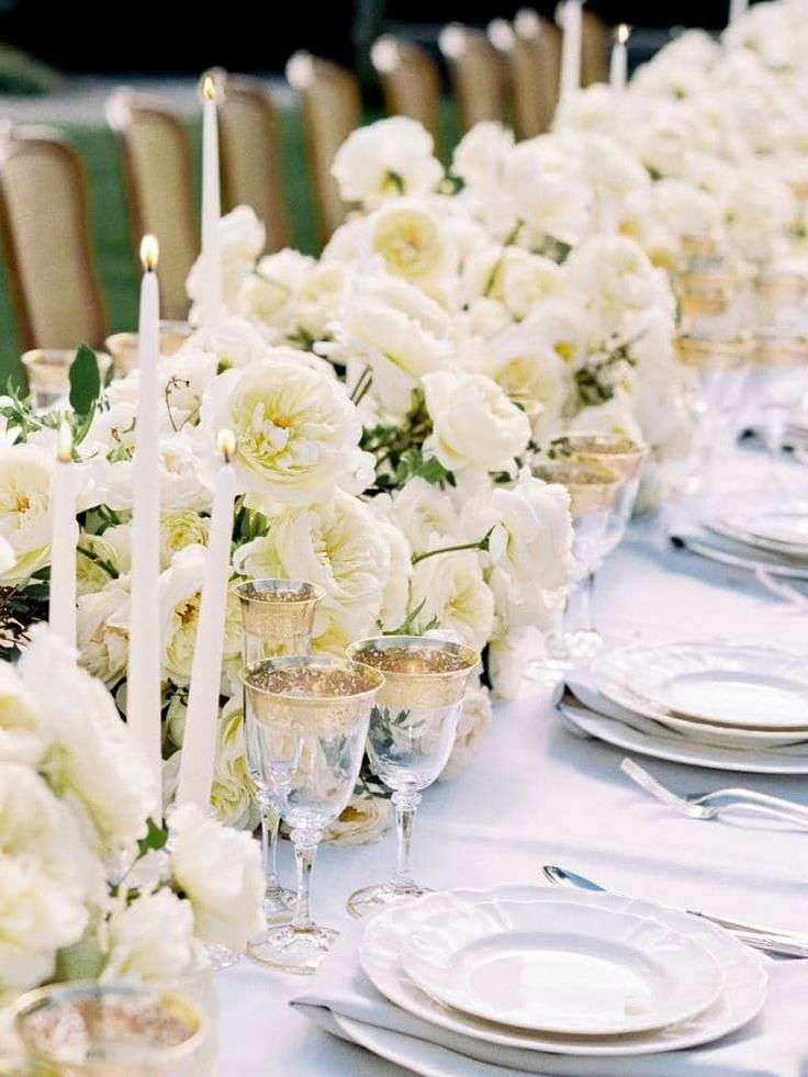 White garden rose table runner with taper candles and gold-rimmed glassware