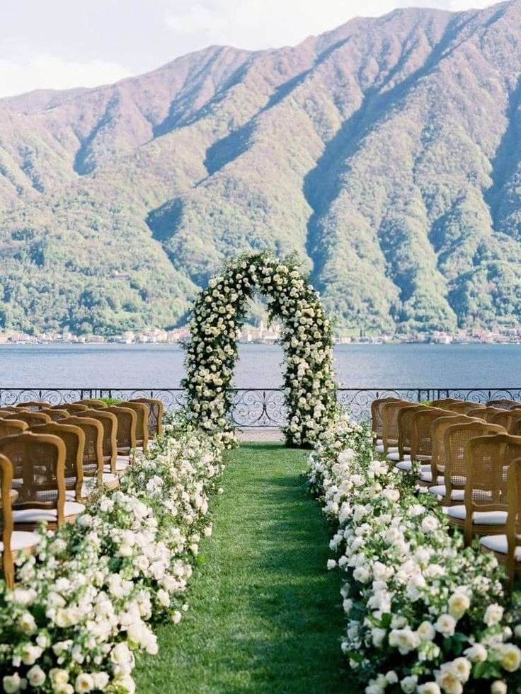 White garden rose ceremony arch overlooking a lake with mountain views