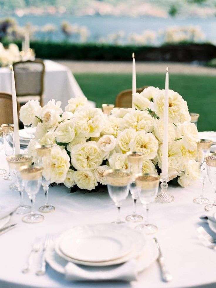 White garden rose centerpiece beside place settings and a handwritten place card