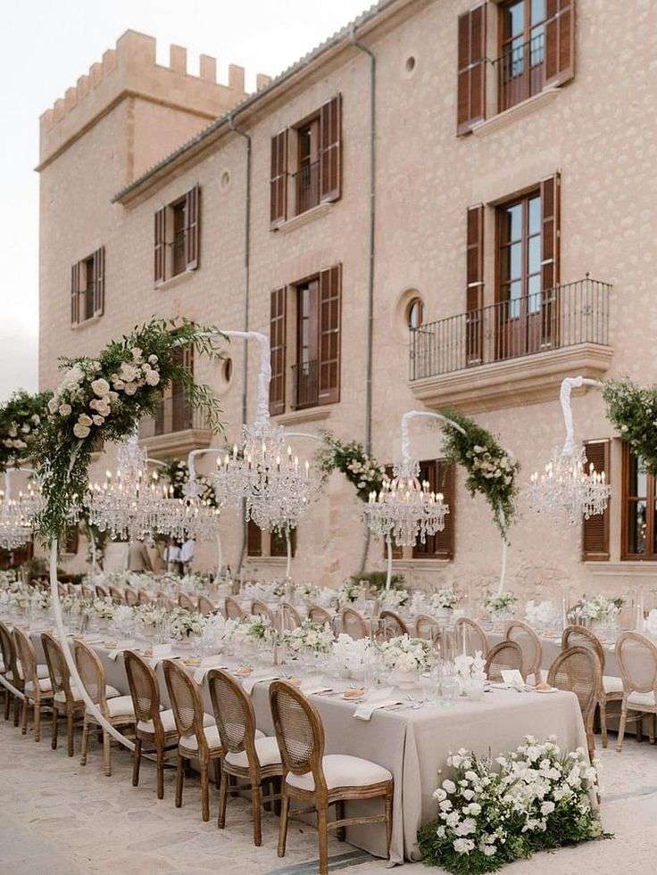 Reception tables and candelabras with garden roses set against the stone castle