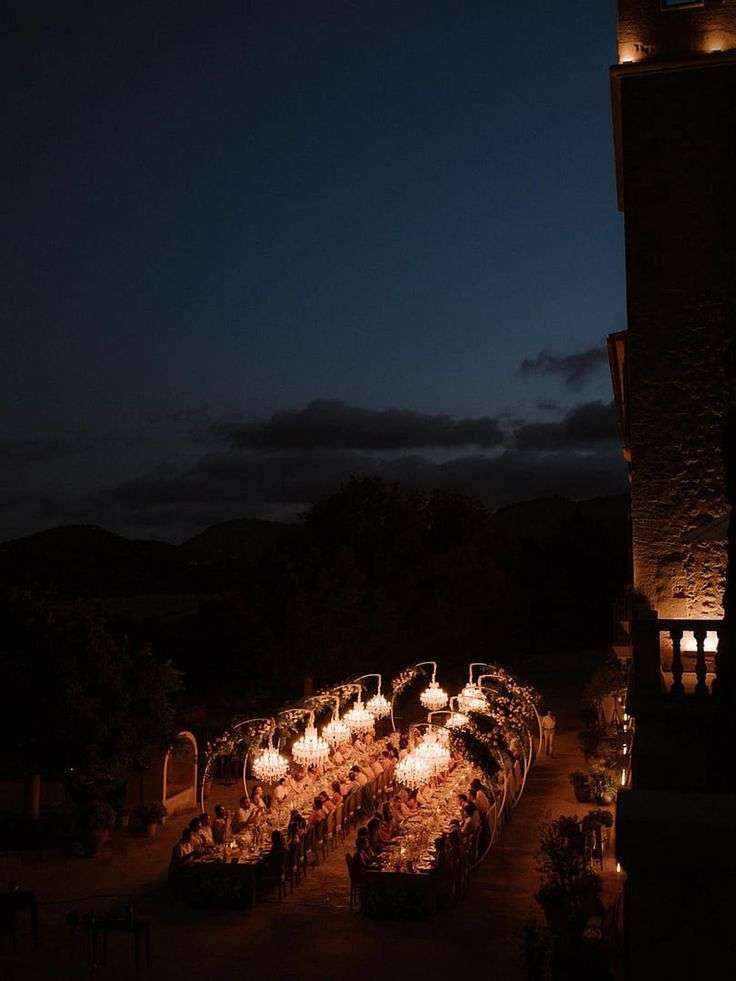 Guests dining at the long candlelit table at Castell Son Claret after dark