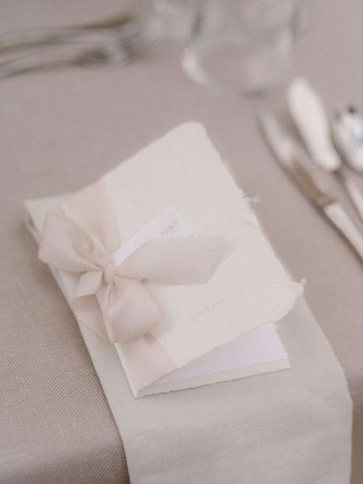 Handwritten wedding place card tied with a ribbon on a linen table runner