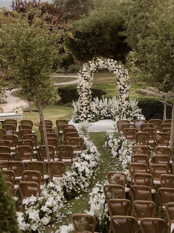Ceremony aisle lined with white flowers leading to a floral arch