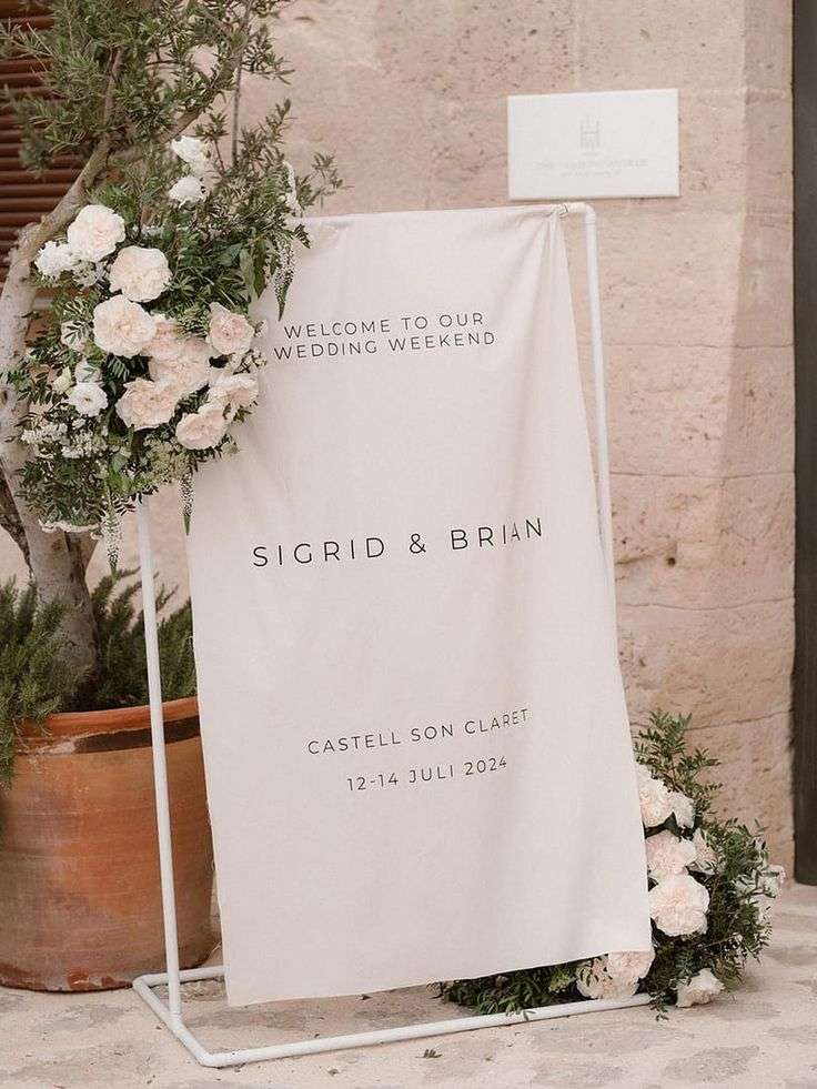 A wedding welcome sign reading Sigrid and Brian, flanked by cream and green floral arrangements.