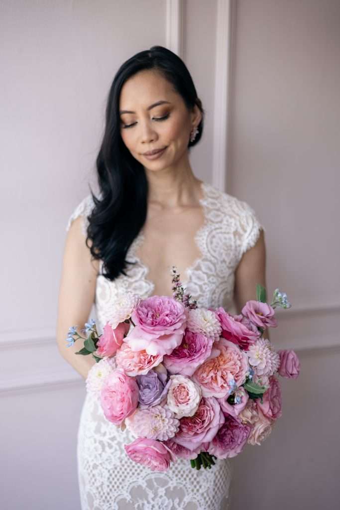 Bride holding a vivid pink garden rose and dahlia bouquet