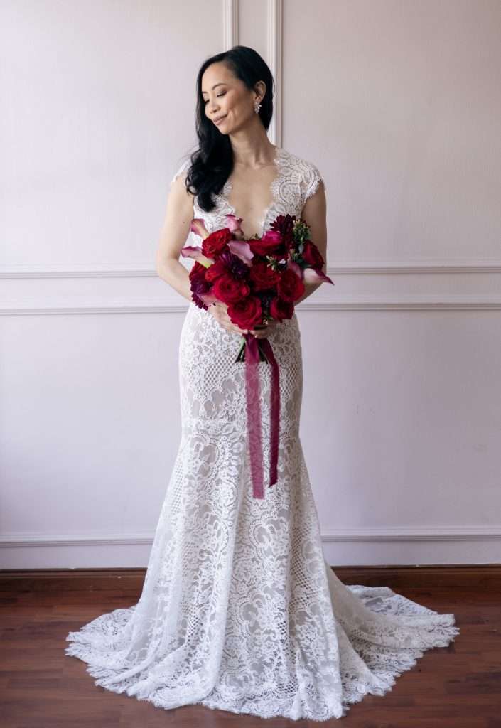 Bride in lace gown holding a deep red garden rose bouquet