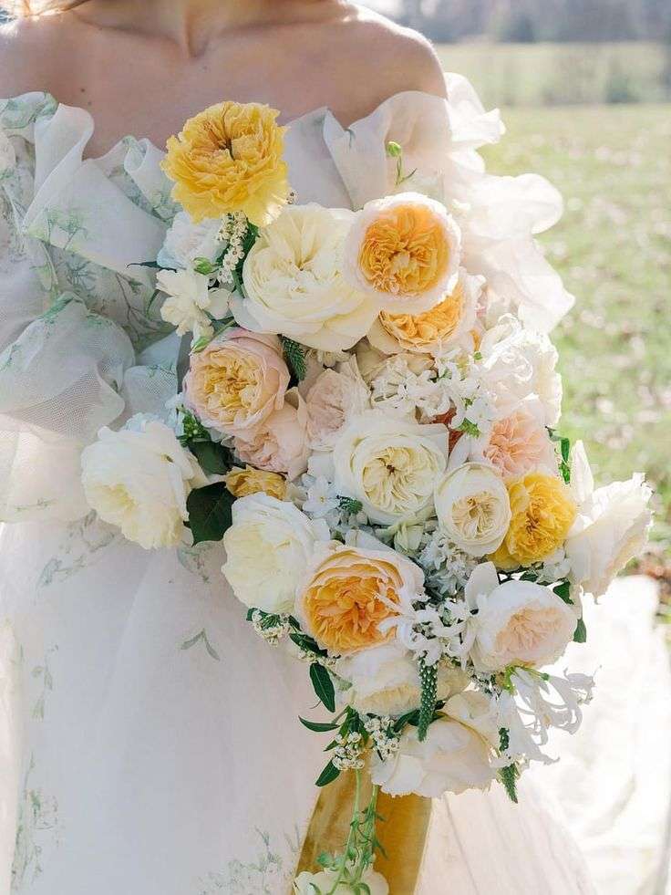Bride in floral off-shoulder gown holding a yellow and ivory garden rose bouquet